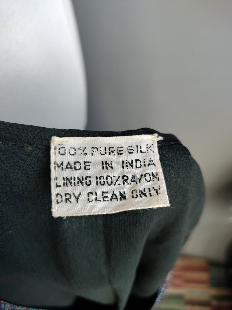 May include: A white tag with black text that reads "100% Pure Silk Made in India Lining 100% Rayon Dry Clean Only".