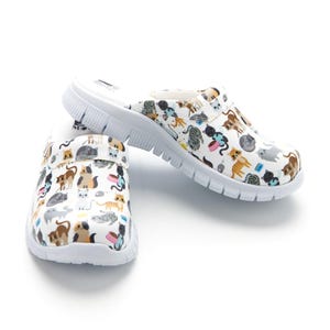 May include: White clogs with a colorful cat pattern. The slip-on shoes have a white sole and a variety of cat illustrations in different poses and colors. The shoes are designed for comfort and casual wear.