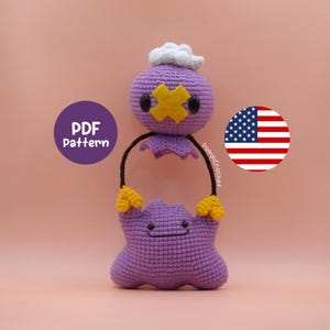 May include: A handmade purple crochet doll with a yellow cross-shaped design on its face and a white cloud-like detail on top. The doll has black arms and is holding a purple shape. The text "PDF Pattern" is visible.