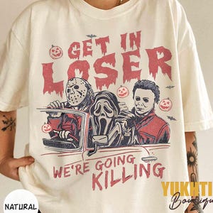 Könnte beinhalten: Cremefarbenes T-Shirt mit einem Halloween-Motiv. Das Design zeigt drei Horrorfilm-Charaktere in einem Auto mit dem Text "GET IN LOSER WE'RE GOING KILLING". Enthält Kürbis- und Fledermaus-Illustrationen.