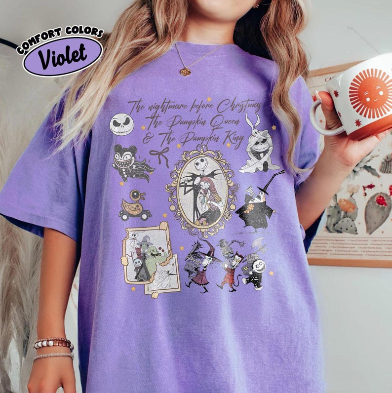 May include: Violet Comfort Colors t-shirt featuring characters from "The Nightmare Before Christmas." The design includes Jack Skellington, Sally, and other characters. The text reads "The Nightmare Before Christmas, The Pumpkin Queen & The Pumpkin King."