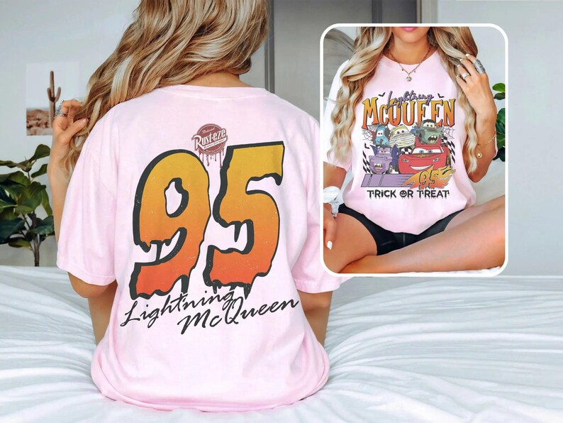 May include: Pale pink t-shirt featuring a large "95" graphic in orange and yellow on the back, with "Lightning McQueen" text. The front displays a Halloween-themed graphic with Cars characters and the words "Trick or Treat".