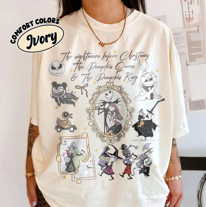 May include: Ivory-colored t-shirt featuring illustrations and text from "The Nightmare Before Christmas." The design includes characters like Jack Skellington, Sally, and the Pumpkin King, with the text "The nightmare before Christmas & The Pumpkin Queen & The Pumpkin King."