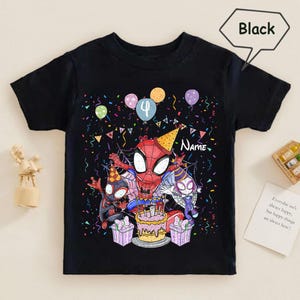 May include: Black t-shirt featuring a colorful graphic of Spider-Man characters celebrating a birthday. The design includes a cake, balloons, and the number 4. The word "Name" is also visible. The shirt is a short-sleeved style.