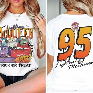 May include: White t-shirt with a Halloween-themed design featuring Lightning McQueen and other Cars characters. The front has the text "Lightning McQueen" and "Trick or Treat". The back displays a large "95" and "Lightning McQueen".