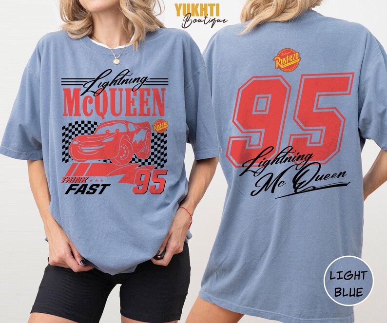 Puede incluir: Camiseta azul claro con dise&ntilde;o de Lightning McQueen. El frente presenta un coche rojo, el texto "Lightning McQueen" y el n&uacute;mero "95". La parte trasera muestra un gran "95" y "Lightning Mc Queen" en rojo y negro.