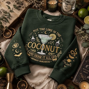 Könnte beinhalten: Ein dunkelgrünes Sweatshirt mit einer zentralen Grafik eines Margaritaglases mit Limettenscheibe, umgeben vom Text "PUT THE LIME IN THE COCONUT AND DRINK IT ALL UP" und "MIDNIGHT MARGARITAS", sowie himmlischen und okkulten Stickereien an den Ärmeln.
