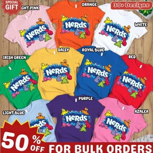 Puede incluir: Una colección de camisetas de manga corta en varios colores, incluyendo rosa claro, naranja, blanco, amarillo margarita, azul real, rojo, azul claro, morado y rosa azalea. Cada camiseta presenta el logotipo de Nerds y gráficos de personajes coloridos.