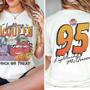 May include: Cream-coloured t-shirt with a Halloween-themed Lightning McQueen design. The front displays the text "Lightning McQueen" and "Trick or Treat" with cartoon cars. The back shows a large "95" and "Lightning McQueen" text.