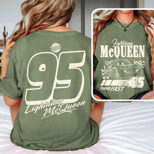 Puede incluir: Camiseta verde oliva con el n&uacute;mero 95 y la inscripci&oacute;n "Lightning McQueen" en la espalda. La parte delantera de la camiseta muestra un gr&aacute;fico de Rayo McQueen con el texto "Think Fast".