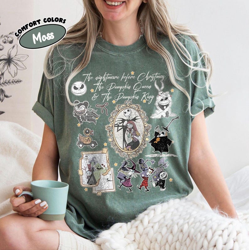 May include: Moss green t-shirt featuring characters from "The Nightmare Before Christmas." The design includes Jack Skellington, Sally, and other characters. The text "The Nightmare Before Christmas & The Pumpkin Queen & The Pumpkin King" is also visible.