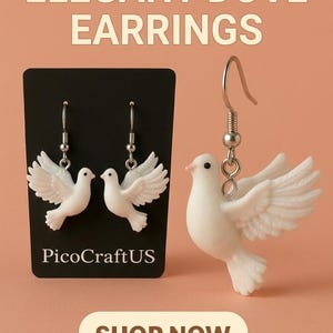 May include: White dove earrings with detailed wing design. The earrings are displayed on a black card with the text "PicoCraftUS" and the words "Elegant Dove Earrings" at the top. The background is a peach color.