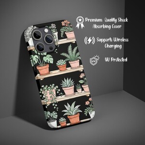 Puede incluir: Funda de tel&eacute;fono negra con una ilustraci&oacute;n bot&aacute;nica de plantas en macetas sobre estantes. La funda tiene un acabado mate e incluye el texto "Premium Quality Shock Absorbing Cover", "Supports Wireless Charging" y "UV Protected".