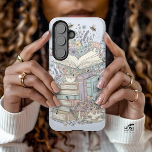 May include: A white phone case with a fantasy illustration of books, flowers, mushrooms, bees, and teacups. The design features an open book, a stack of books, and teacups. The case has a camera module with three lenses.