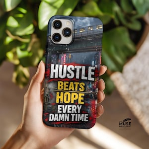 May include: A smartphone case with a cityscape design and the text "Hustle Beats Hope Every Damn Time" in red, yellow, and white. The case has a black border and a glossy finish. The Muse Merchant logo is in the bottom right corner.