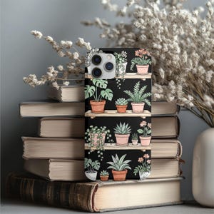 Puede incluir: Funda de tel&eacute;fono negra con dise&ntilde;o bot&aacute;nico. Presenta ilustraciones de plantas en macetas sobre estantes de madera. El dise&ntilde;o incluye varias plantas verdes en macetas de terracota sobre un fondo negro. La funda tiene una est&eacute;tica inspirada en la naturaleza.