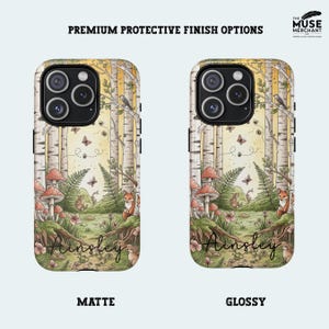 Op de afbeelding: Twee telefoonhoesjes met een bossc&egrave;ne-ontwerp. De hoesjes hebben een berkenbos met paddenstoelen, vossen, vlinders en de naam "Ainsley". Verkrijgbaar in matte en glanzende afwerking. De tekst "Premium Protective Finish Options" staat bovenaan.