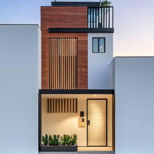 May include: Contemporary three-storey house with a minimalist design. The facade features white walls, wooden panels, and black accents. A small balcony and a front door are visible. The house has a modern architectural style.