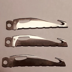 May include: Three silver metal saw blades with a hook and a hole for attachment. The blades have a serrated edge and a curved hook at the end. The blades are arranged in a vertical stack.