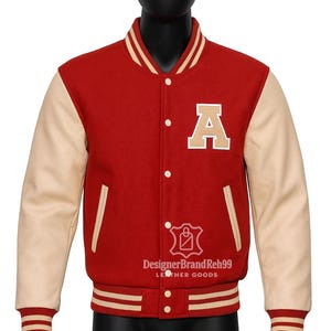 May include: Red and cream varsity jacket with the letter "A" on the chest. The jacket has cream-coloured sleeves and striped trim on the collar, cuffs, and waist. The jacket is displayed on a mannequin.