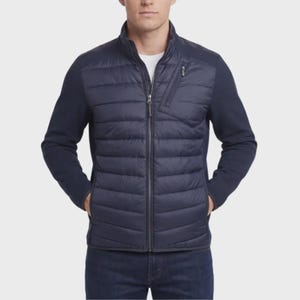 Puede incluir: Una chaqueta híbrida azul marino que presenta un panel frontal acolchado y aislado con un bolsillo vertical con cremallera en el pecho y mangas de punto liso de color sólido. La chaqueta tiene una cremallera central y cuello alzado.