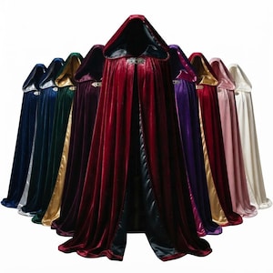 May include: A collection of floor-length hooded cloaks made of velvet fabric, displayed in a fan arrangement. Each cloak features a contrasting satin-like lining and a decorative metal clasp at the neck, available in red, blue, green, purple, pink, and white.