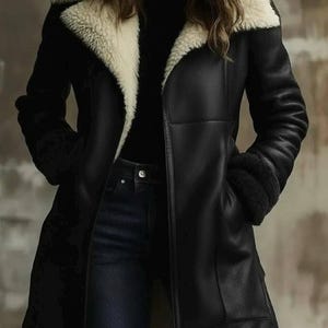 Peut inclure: Manteau en similicuir noir avec col et poignets en fausse fourrure crème. Le manteau est long, de coupe ajustée et possède des poches. Le modèle porte un col roulé noir et un jean délavé foncé. Un vêtement d'extérieur élégant.