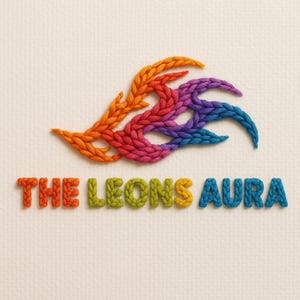 May include: A colorful, embroidered design featuring a stylized, abstract shape in orange, red, pink, purple, and blue. Below, the words "THE LEONS AURA" are embroidered in orange, green, yellow, and blue, respectively, against a textured, off-white background.