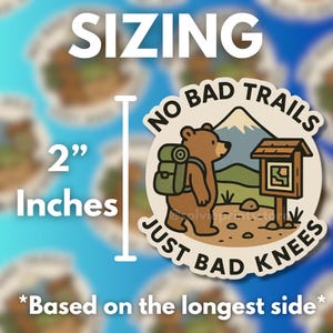 Puede incluir: Adhesivo redondo con un oso pardo con mochila, de pie cerca de una se&ntilde;al de sendero, con el texto "NO BAD TRAILS JUST BAD KNEES". El adhesivo mide 5.08 cm, basado en el lado m&aacute;s largo.