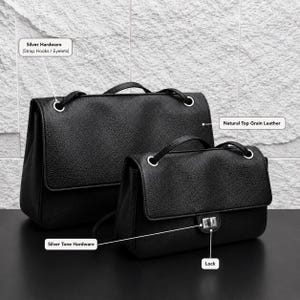 Two black top grain leather handbags shown with labeled features including natural top grain leather, silver hardware eyelets, silver tone lock closure, and structured flap design. The bags are displayed on a dark surface with a textured stone background, highlighting premium craftsmanship and everyday elegance.