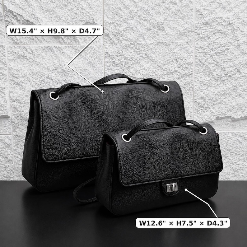 Black top grain leather shoulder bags in two sizes displayed on a dark tabletop against a textured stone wall. Size dimensions are highlighted: Large bag measures 15.4" W x 9.8" H x 4.7" D, and small bag measures 12.6" W x 7.5" H x 4.3" D. Features a minimalist silhouette with silver eyelets and structured flap design.