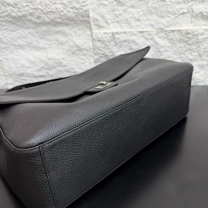 Close-up view of a black leather shoulder handbag showing the structured base, smooth edges, textured leather finish, and elegant flap design. The premium craftsmanship and clean silhouette highlight this minimalist purse as a stylish everyday accessory for modern fashion lovers.