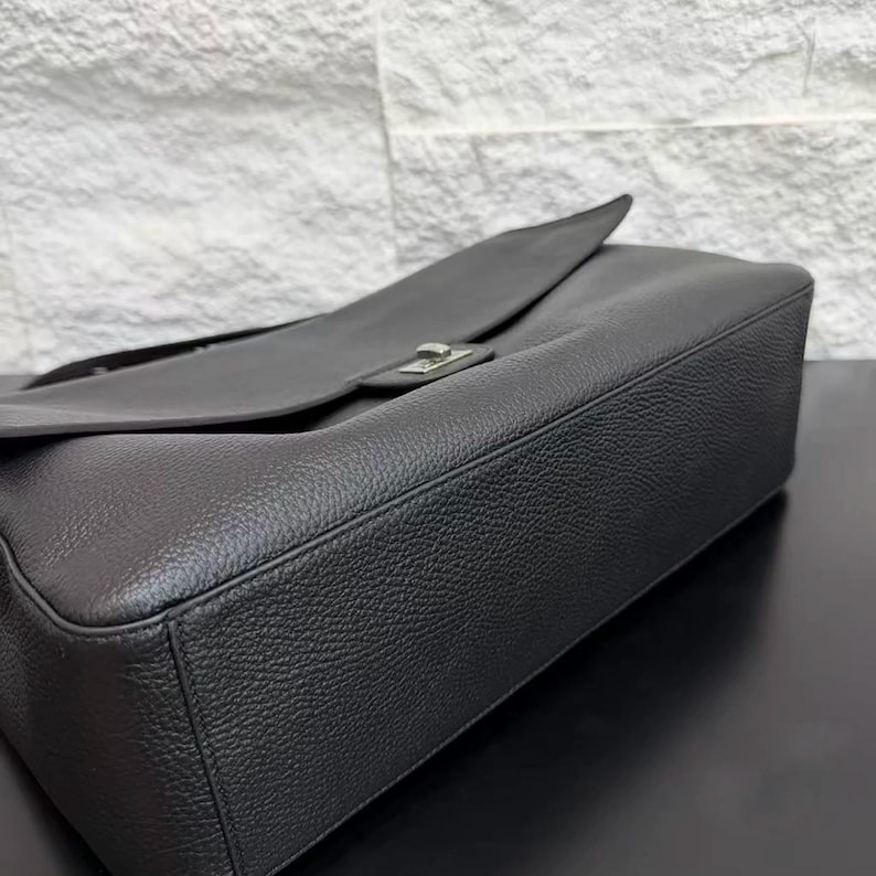 Close-up view of a black leather shoulder handbag showing the structured base, smooth edges, textured leather finish, and elegant flap design. The premium craftsmanship and clean silhouette highlight this minimalist purse as a stylish everyday accessory for modern fashion lovers.