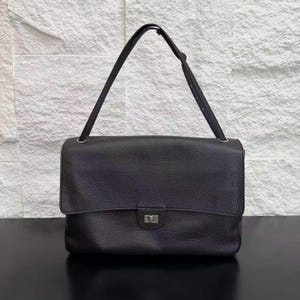 Front view of a black leather shoulder handbag featuring a wide flap cover, silver buckle lock, textured finish, and sleek design. A timeless everyday purse that blends modern elegance, practicality, and premium style for women’s fashion.