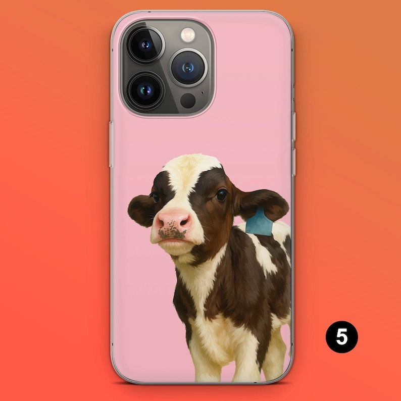 May include: A pink phone case featuring a brown and white calf with a blue ear tag. The calf has a pink nose and is set against a pink background. The phone case has a clear border and a camera cutout.