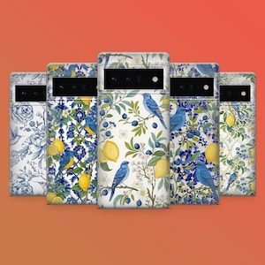 Peut inclure: Plusieurs coques de téléphone avec des motifs floraux et d'oiseaux. Les coques présentent des citrons, des oiseaux bleus et des motifs floraux dans des tons de bleu, jaune et blanc. Les coques sont disposées en rangée sur un fond orange.