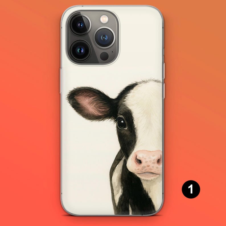 May include: A white phone case featuring a watercolor illustration of a black and white cow's face. The cow's eye, ear, and pink nose are visible. The phone case has a clear border and a camera cutout.