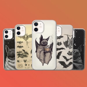 May include: A collection of phone cases with bat-themed designs. One case features a bat wrapped in a shawl, holding a cup of coffee. Other cases display bat illustrations and a starry night design. The cases are in various colors.
