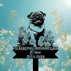 May include: Black metal garden stake featuring a pug dog design surrounded by daisies. The text reads "IN LOVING MEMORY OF Orion 2014-2024". The background is a soft blue sky with white flowers.