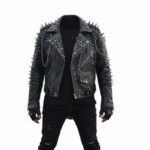 May include: Black leather jacket adorned with silver spikes and studs. It has a notched collar, multiple pockets, and a zip closure. Silver chains hang from the shoulders. A classic biker jacket style.
