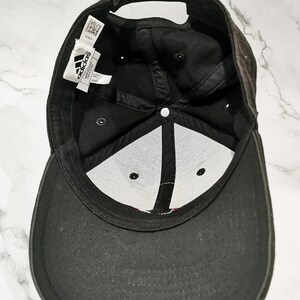 Puede incluir: Gorra de b&eacute;isbol Adidas negra. La gorra tiene una visera curva y una correa ajustable. El interior tiene un panel blanco con costuras negras y el logotipo de Adidas. La gorra est&aacute; hecha de una tela duradera.