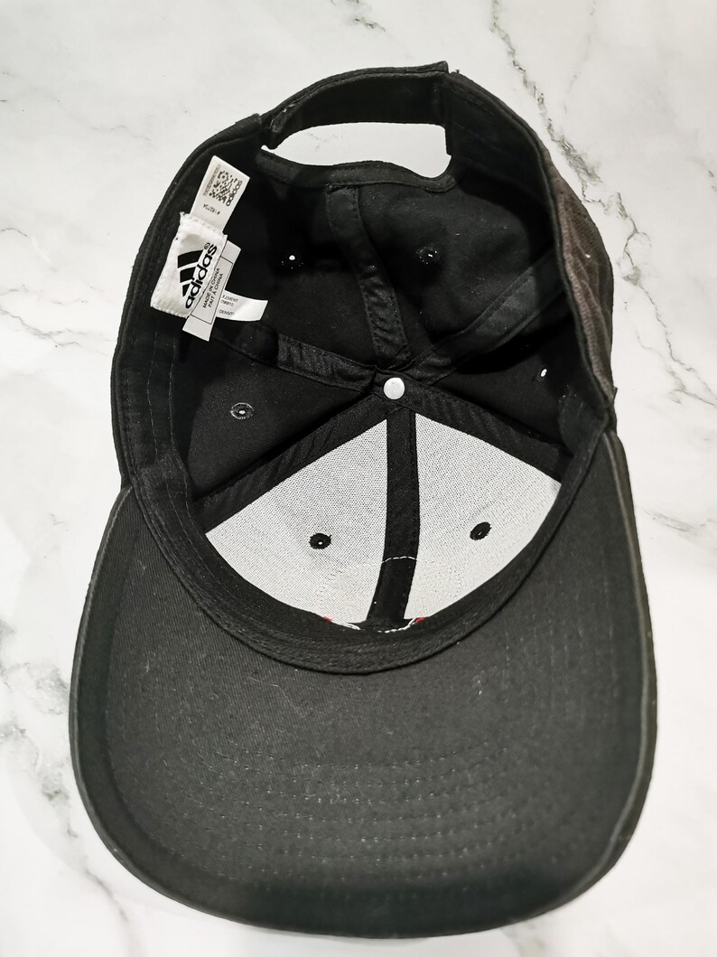 Puede incluir: Gorra de b&eacute;isbol Adidas negra. La gorra tiene una visera curva y una correa ajustable. El interior tiene un panel blanco con costuras negras y el logotipo de Adidas. La gorra est&aacute; hecha de una tela duradera.