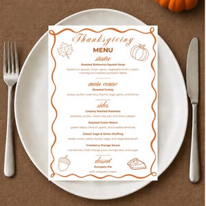 Könnte beinhalten: Eine rechteckige Thanksgiving-Menükarte mit gewelltem orangefarbenem Rand, verziert mit Illustrationen von einem Blatt, Kürbis, Eichel und Kuchenstück. Der Text listet Gänge wie Kürbissuppe, gebratenen Truthahn und Kürbiskuchen auf.