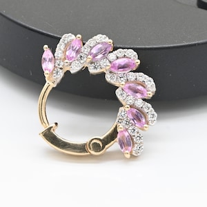 May include: A gold-toned hinged hoop earring with a floral design. The earring features marquise-cut pink gemstones and clear, round-cut gemstones. The gemstones are set in a delicate, leaf-like pattern, creating a sparkling, elegant accessory.