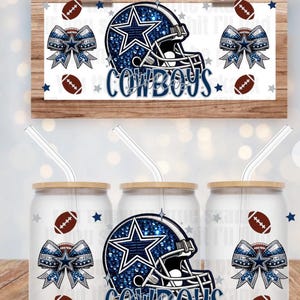 Puede incluir: Un letrero de madera y tres vasos de vidrio con tapas y pajitas. El letrero y los vasos presentan un diseño de casco de fútbol de los Dallas Cowboys en azul y blanco con la palabra "Cowboys". El diseño incluye balones de fútbol y lazos.
