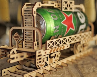 May include: A wooden model train carrying a green and silver can of beer. The train is made of light brown wood and sits on a wooden track. The beer can has a red star and the word "Heineken".