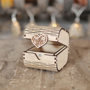 May include: A small, open wooden chest with a heart-shaped embellishment. The chest is made of light-colored wood and features a decorative heart with floral cutouts. The chest is designed with a hinged lid and a small clasp.