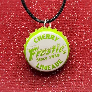 May include: A green and white bottle cap necklace with the words "Cherry Frostie Since 1939 Limeade" on it.
