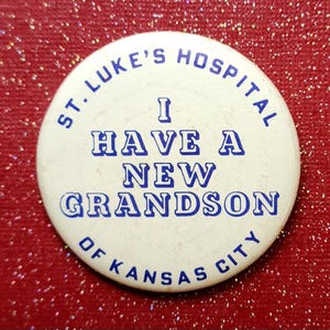 May include: A white button with blue text that reads "St. Luke's Hospital I Have A New Grandson Of Kansas City".