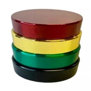 May include: A stack of four colorful containers. The top container is a shiny red, followed by gold, green, and black. The containers are round with a flat top and base, and the colors are vibrant and eye-catching.